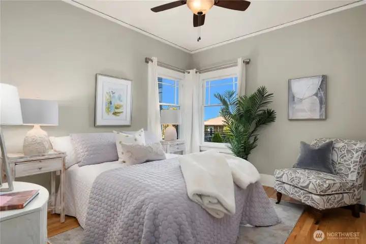 This restful bedroom boasts corner windows, soft natural light, and space for cozy seating.