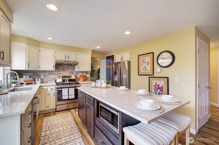 The island includes bar stool seating, under counter microwave, drawers on end and roll out garbage/recycle bins.