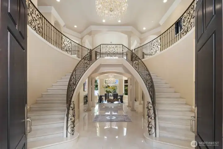 Dual staircases showcasing master crafted metal railings add to the elegance of the home, creating a welcoming and luxurious atmosphere. The intricate designs draw the eye and contribute to the overall refined ambiance of the property.