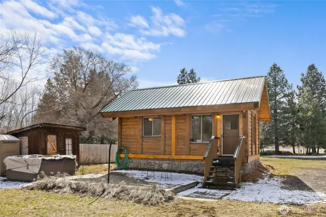 Front view of cabin, patio, hot tub and additional storage shed
