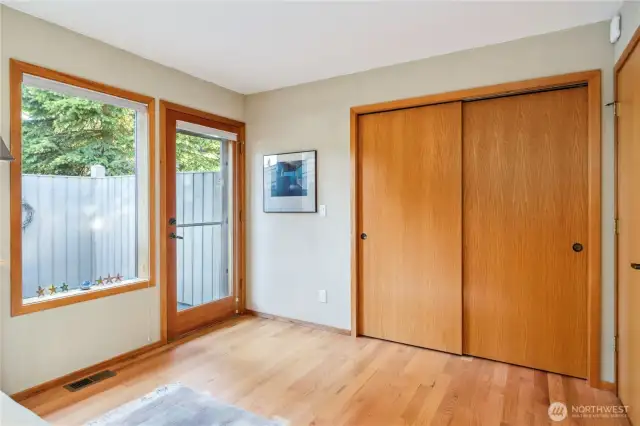 The guest bedroom/flex room with lot of closet space, beautiful hardwood floors, and outdoor access to the lovely fenced-in patio, that also has an entrance beyond to the front driveway.