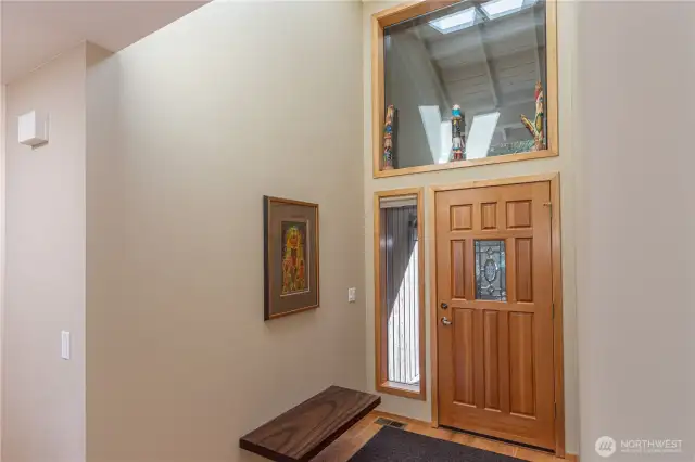 The entryway is spacious with vaulted ceilings, natural light and a beautiful free-floating wood bench and real hardwood floors.