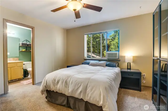 The primary bedroom can easily accommodate a king size bed with plenty of room for additional furniture without sacrificing the ability to reach the ensuite bath. Note the ceiling fan to keep cool air moving from your window AC unit (that stays with the home!)