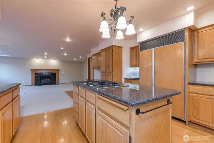 The kitchen features hardwood floors, black granite counters, s Sub Zero refrigerator, a gas 4 burner downdraft cooktop