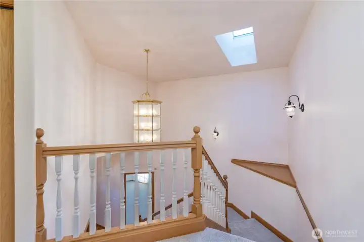 The staircase features a custom chandelier and a skylight, as well as wall sconce lighting