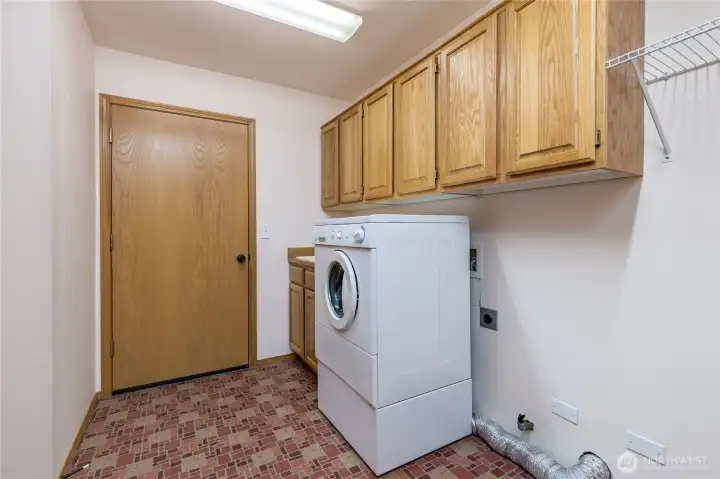 The laundry room has oak cabinets and easy to maintain vinyl flooring