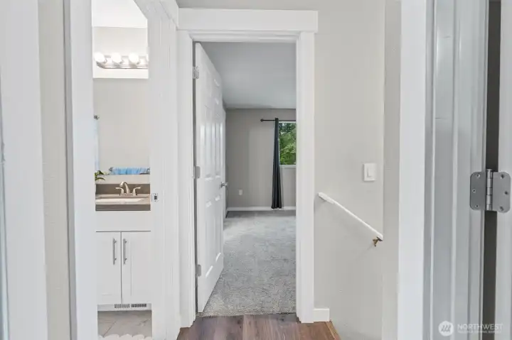 Upstairs landing showing the hall bathroom to the left, primary with ensuite straight ahead, and bedroom two on the right.