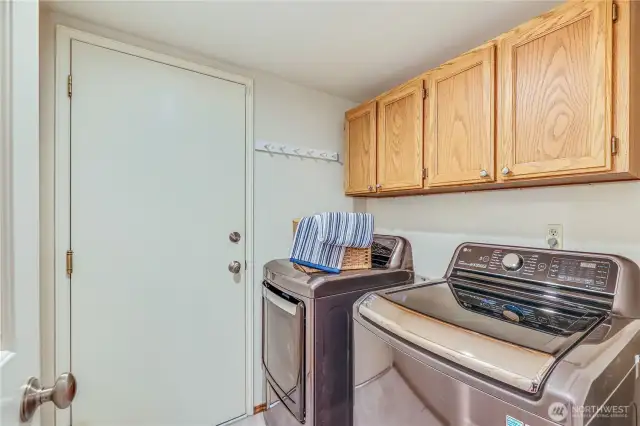 A dedicated laundry room provides ample cabinetry for storage and convenient access to the garage. Equipped with a full-size washer and dryer, this space makes laundry tasks efficient and organized