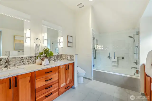 The updated primary bathroom features a double vanity, modern fixtures, heated tile floor and a well-lit mirror. The neutral tones and ample storage make this space both functional and stylish.