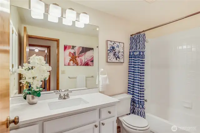 This updated bathroom features a sleek vanity, framed mirror, and modern lighting. A combination of neutral colors and quality materials makes this space feel fresh and contemporary.