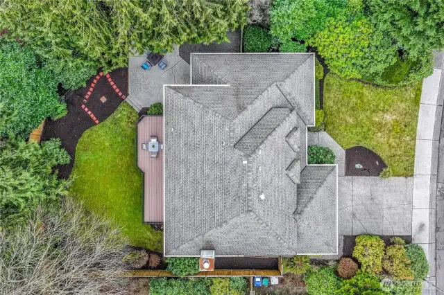 This aerial perspective showcases the property’s thoughtfully designed outdoor layout, including the spacious deck, lush lawn, and private patio area. The mature trees provide natural shade and tranquility.