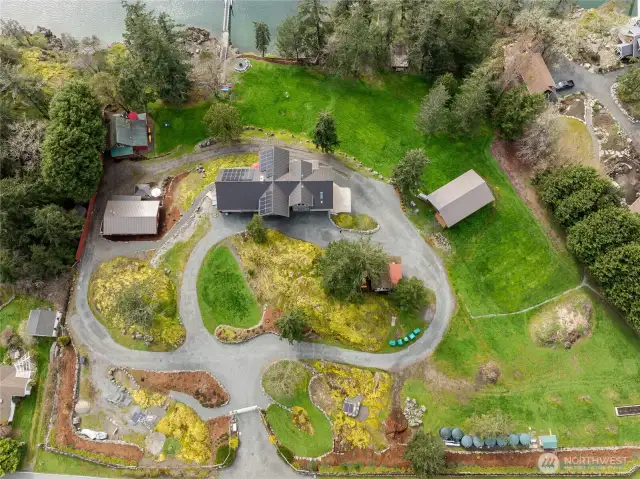 Manicured grounds with circular driveway. Access main residence, guest homes and additional covered structure (right side of photo) This structure currently houses an RV and has an expansive deck for outdoor enjoyment.