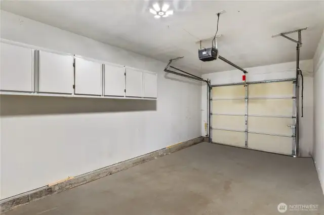 Attached garage has ample storage, with cabinets along walls as well as a recessed space that is just to the right.
