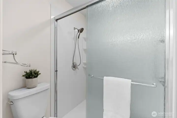 Primary shower with sleek walk-in sliding glass doors.