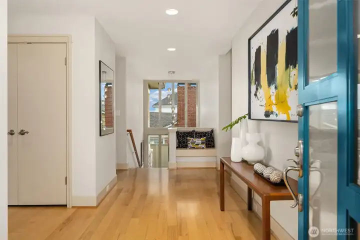 This entry photo pulls everything together nicely.  A private entry courtyard behind us (filled with bulbs and perennials) leads to the front door, which opens into this gracious formal entry.  The doorway behind the coat closet on the left leads past the pantry closet into the kitchen.  Stepping immediately to our left would take us into living/dining spaces.  A double-height south-facing window welcomes light into the entry space and stairs leading to the lower level.  For now, let's check out the upper bedrooms/bathrooms, which are just a few steps up through that doorway on the right...