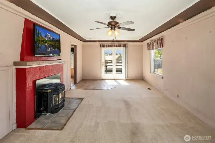 Living room with cozy warm pellet stove, attached TV stays. Doors open to large entertaining deck looking out to Mt Peoh to the south. There is also a sun awning attached to the home over the deck that will help keep you comfortable all summer long.