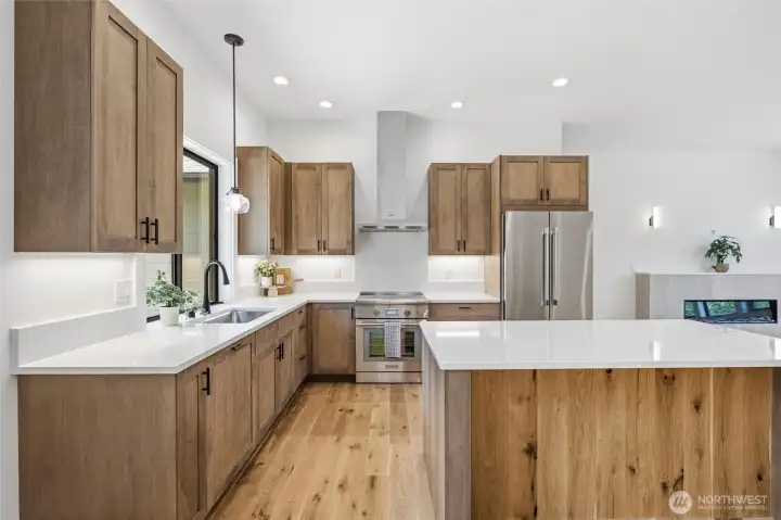 Open kitchen layout with abundant counter space, modern lighting, and sleek design details. Open kitchen layout with abundant counter space, modern lighting, and sleek design details.