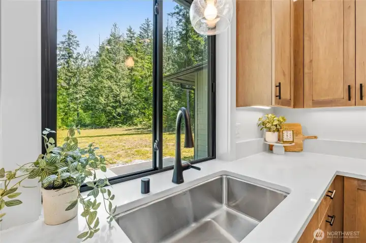 Kitchen with scenic background views & stylish matte black fixtures. Kitchen with scenic background views & stylish matte black fixtures.