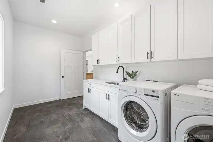 Dedicated laundry space with ample storage and utility sink area. Dedicated laundry space with ample storage and utility sink area.