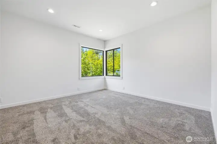 Bright primary bedroom with large windows and modern flooring. Bright primary bedroom with large windows and modern flooring.