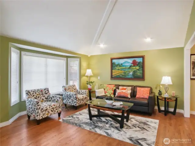 Living room features garden windows and gleeming hardwood floor.