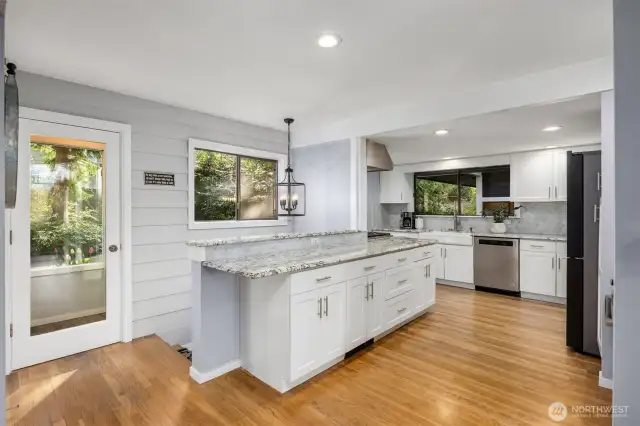 The updated L-shaped kitchen offers a functional and efficient layout, featuring sleek countertops, contemporary cabinetry, and stainless steel appliances. The open design maximizes workspace while maintaining a seamless flow into the adjacent dining and living areas.