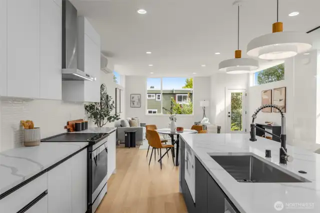 Designer pendant lighting adds an artistic glow above the island, complementing the clean lines and polished finishes.