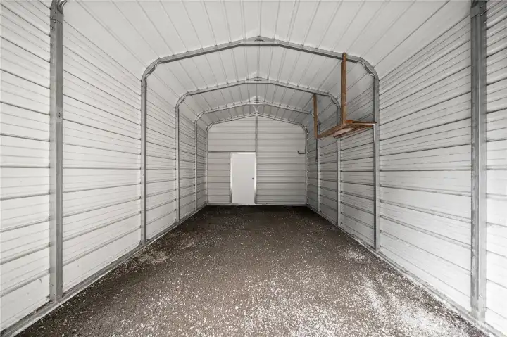 Fully enclosed metal carport with roll up metal garage door.