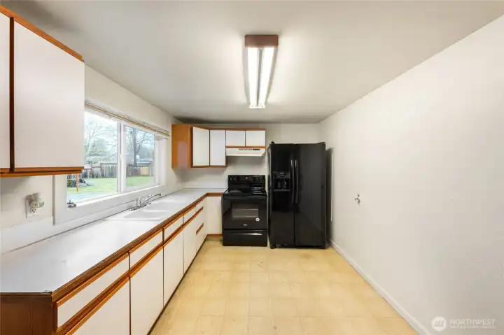 Spacious galley kitchen with extensive cabinetry and counter space, offering excellent functionality and potial for customization