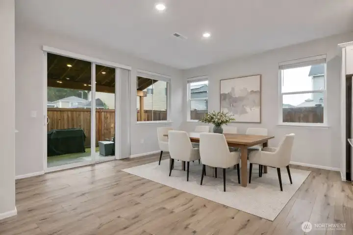 Bright dining area connected to the kitchen, leading to a private fenced and covered patio - Virtual stage.