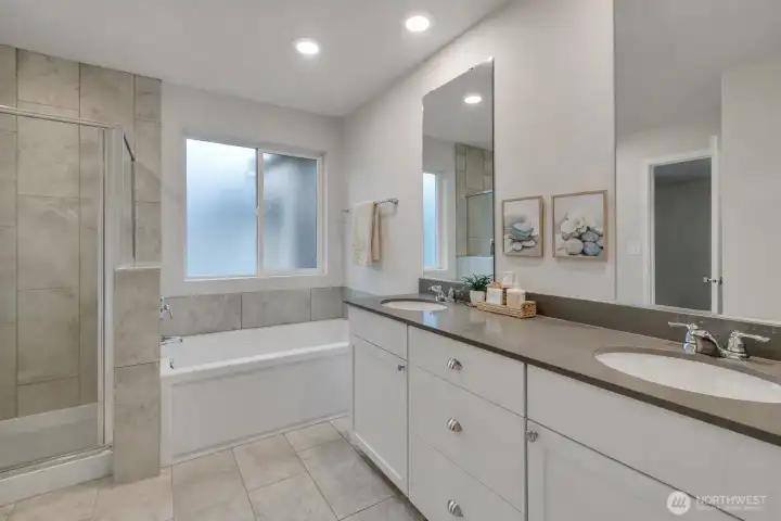 Luxurious primary bathroom with dual sinks, a soaking tub, and a separate walk-in shower - virtual staged.