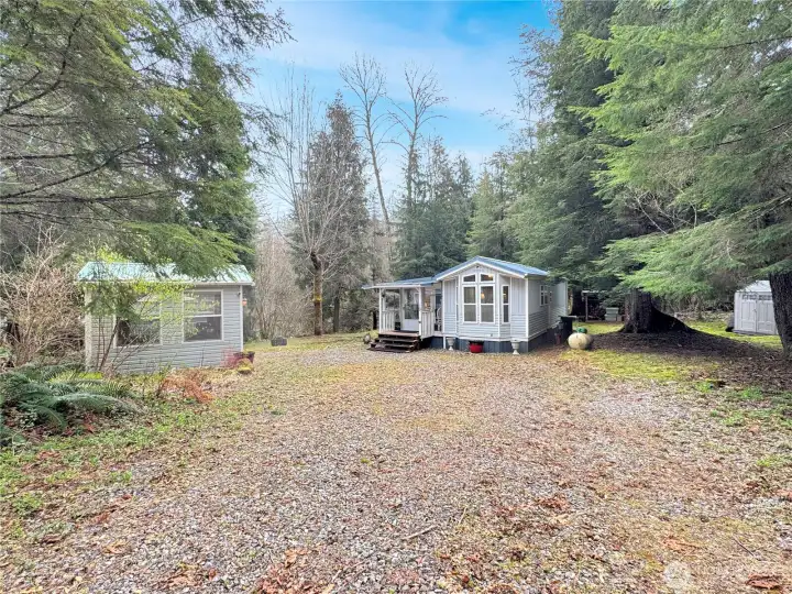 Gravel driveway/parking area lead to the park model which is set back on the lot