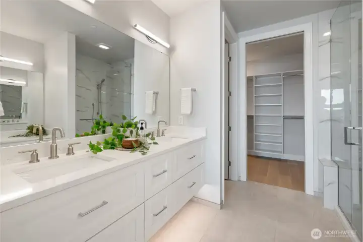 Spa-inspired primary bath with heated floors, double sinks, walk-in closet with custom built-ins, and dedicated vanity area