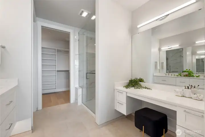 Spa-inspired primary bath with heated floors, double sinks, walk-in closet with custom built-ins, and dedicated vanity area
