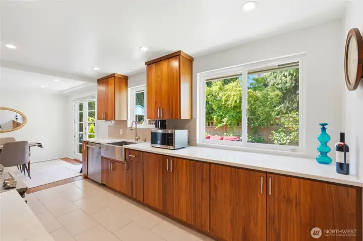The stunning kitchen features custom walnut cabinetry, quartz countertops, stainless steel appliances, recessed lighting, & abundant storage