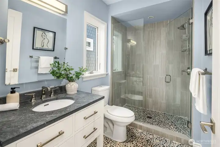 Stone and ceramic floors and shower walls, echoing natural outdoor elements, shape this serene private bath.