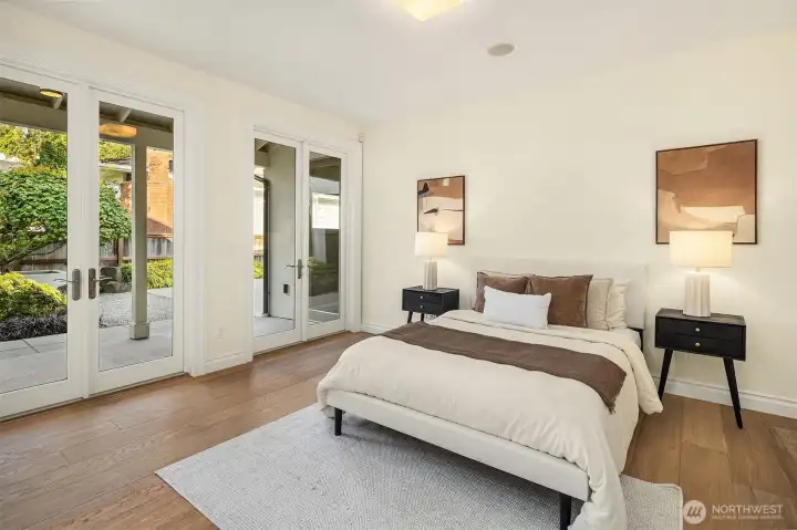 Back on the main level, this generously sized ensuite bedroom offers its own private bath and elegant sets of French doors, opening directly onto the tranquil, non-water side of the garden.