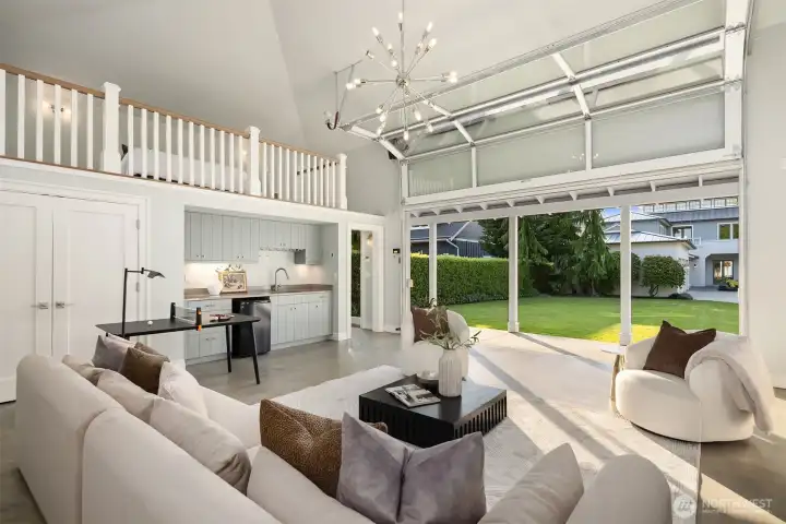 Garage doors open directly onto the lawn, creating a seamless indoor-outdoor flow. Inside, a convenient kitchenette, loft bedroom, and full bath are complemented by polished concrete floors and vaulted ceilings for a clean aesthetic—an adaptable space perfect for ping-pong, an art studio, a separate rec room, or whatever lifestyle needs arise.