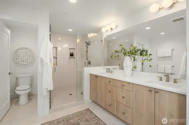 Primary en suite bathroom with dual vanities, water closet, standalone tub and large shower