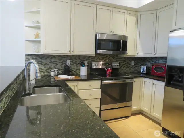 Darker granite countertops and glass backsplashes contrast well with the white cabinetry.