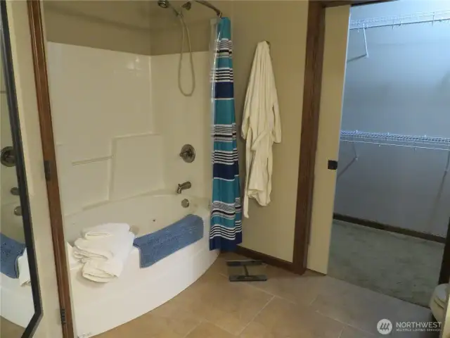 Jetted tub/jakuzzi in the primary full bathroom.  Spacious walk-in closet shown here with a pocket door.