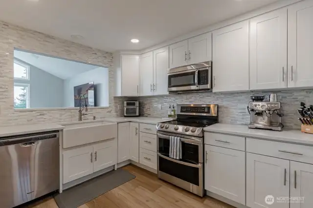 Beautiful white cabinetry, full height backsplash, and stainless appliances complement this kitchen.