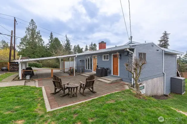 Front exterior with a large patio. This home, ideally located just minutes from the beach, offers the ultimate Pacific Northwest lifestyle.