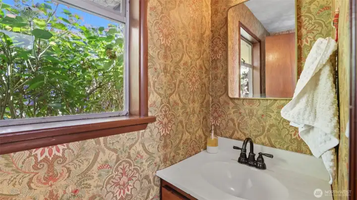 Half bath off the kitchen with classic wallpaper detail.