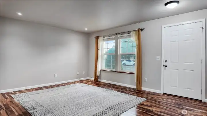 Spacious living room with updated flooring, large windows, and flexible layout options.