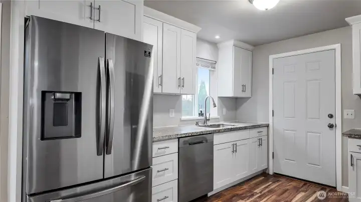 Full kitchen view showcasing stainless steel refrigerator, dishwasher, ample cabinetry, and clean finishes
