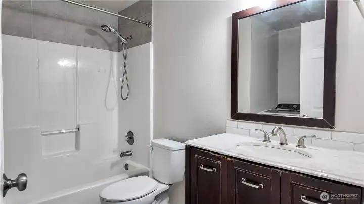 Full bathroom featuring tub and shower combo, updated vanity, and clean finishes.