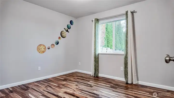 Bedroom with window featuring updated flooring and natural light.