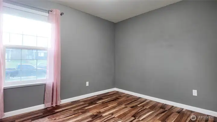 Bedroom featuring window, updated flooring, and neutral tones.