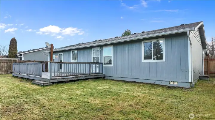 Rear exterior featuring a spacious deck and fully fenced yard, ideal for outdoor use.